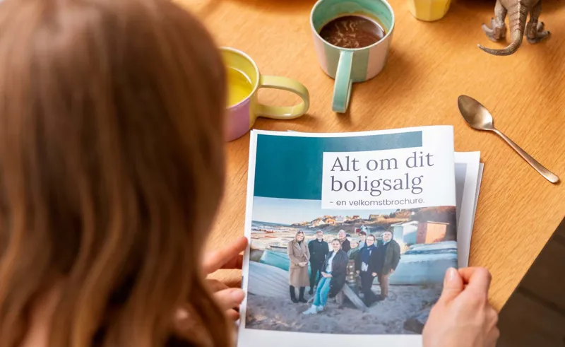 Kvinde læser velkomstbrochuren, "Alt om dit boligsalg" fra danbolig