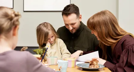 Familie med to børn sidder ved bord og kigger i papirer