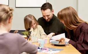 Familie med to børn sidder ved bord og kigger i papirer
