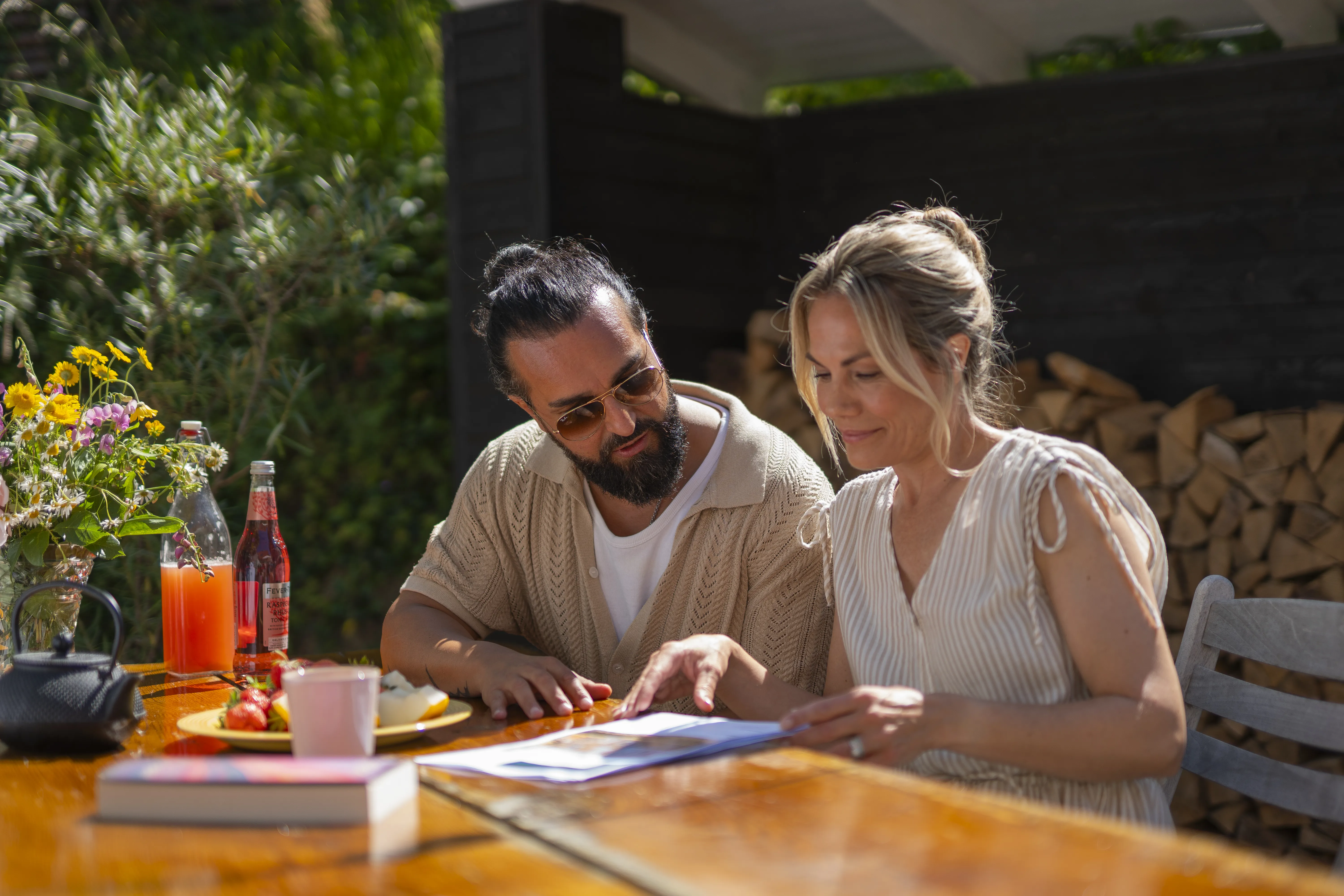 Par sidder ved bord i haven og kigger på papirer