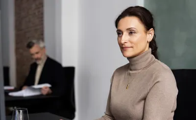 Kvindelig ejendomsmægler sidder ved skrivebord og arbejder på computer