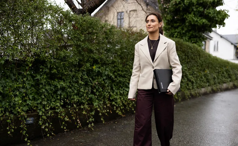 Ejendomsmægler med lys blazer går på villavej