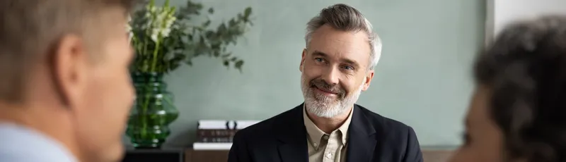 Ejendomsmægler sidder foran to personer, der får boligrådgivning