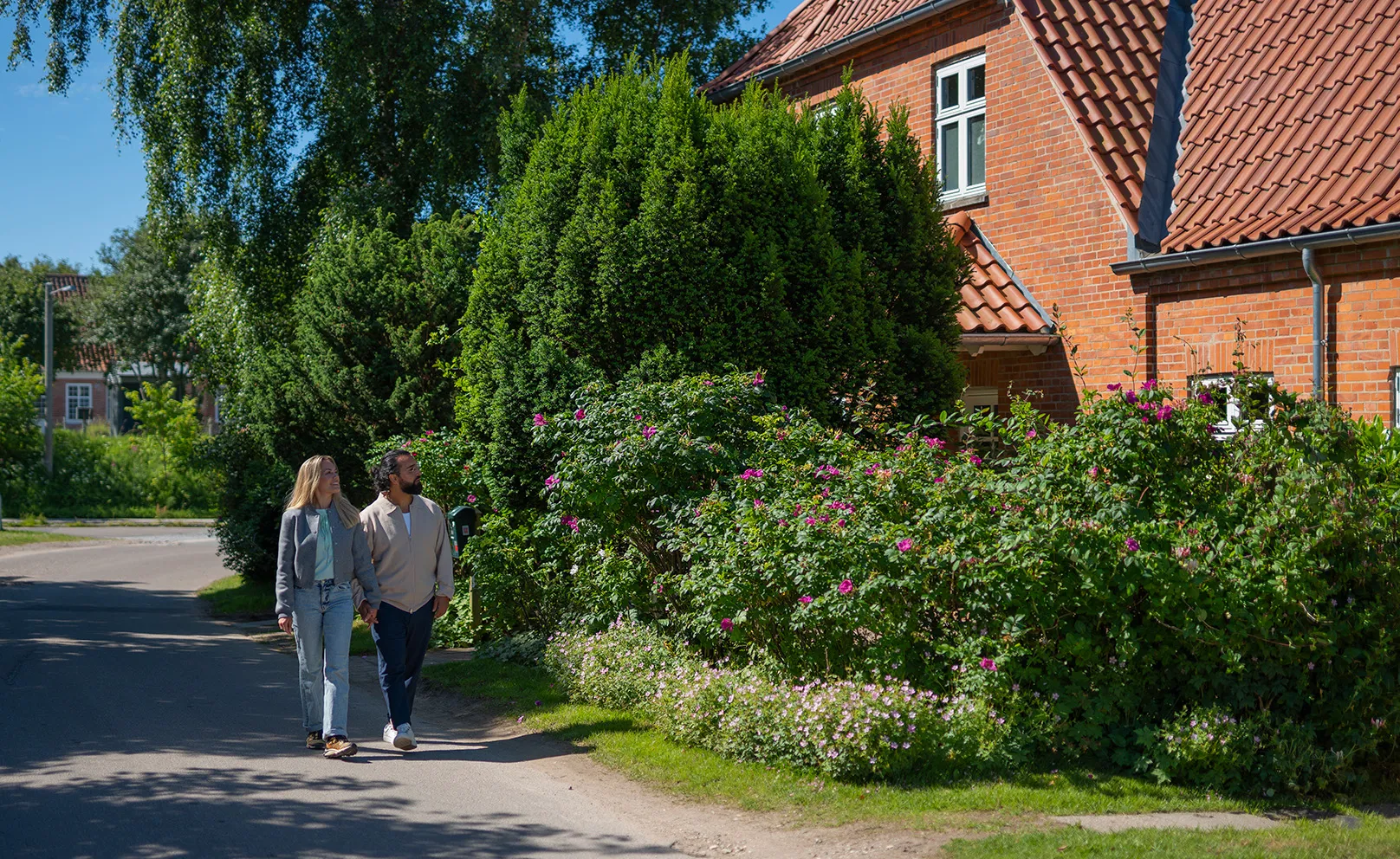 Par går hånd i hånd på villavej og kigger på boliger