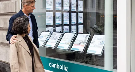 To personer kigger på boliger i vinduet hos en danbolig-butik