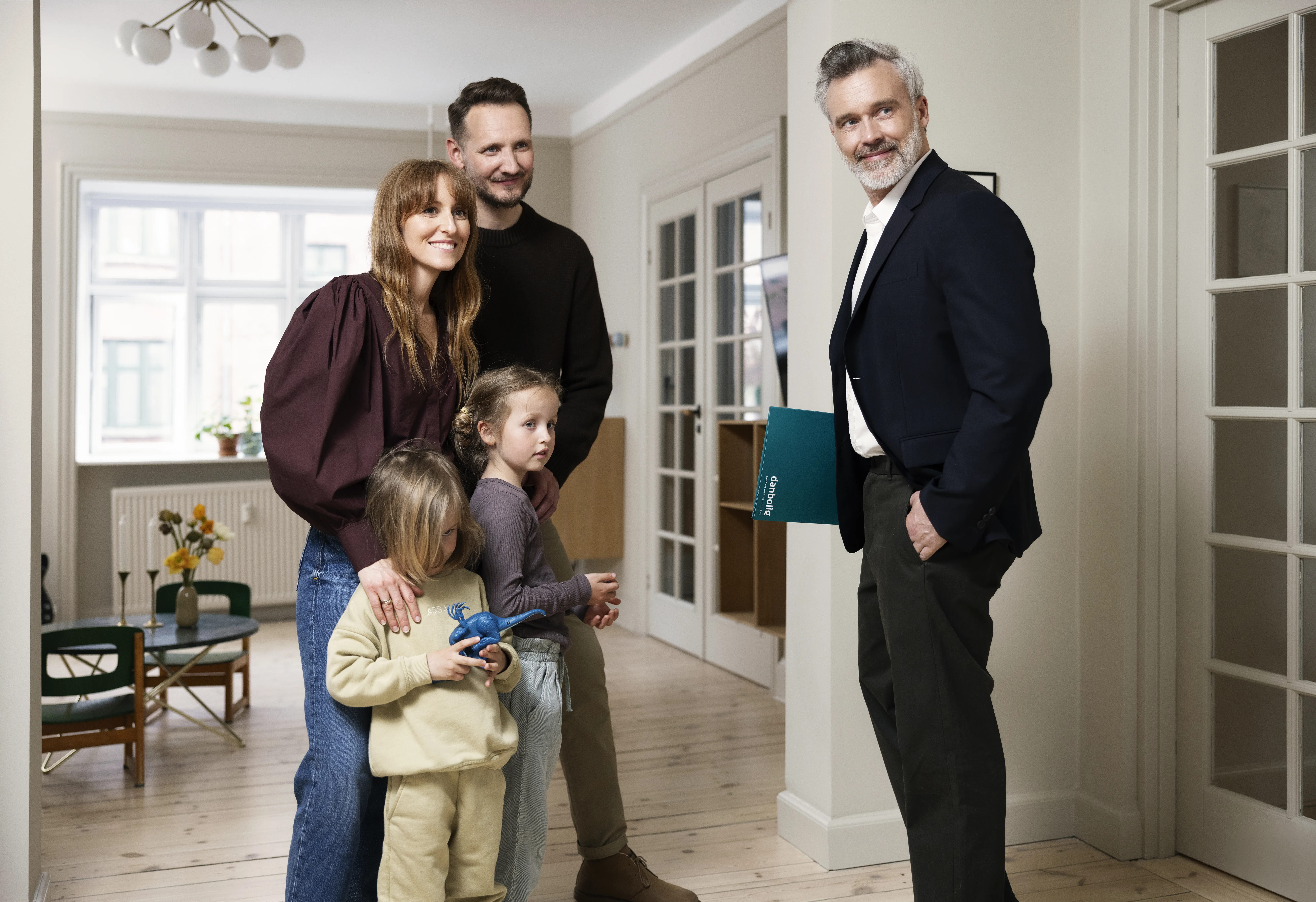 Ejendomsmægler står med to personer og to børn i stuen
