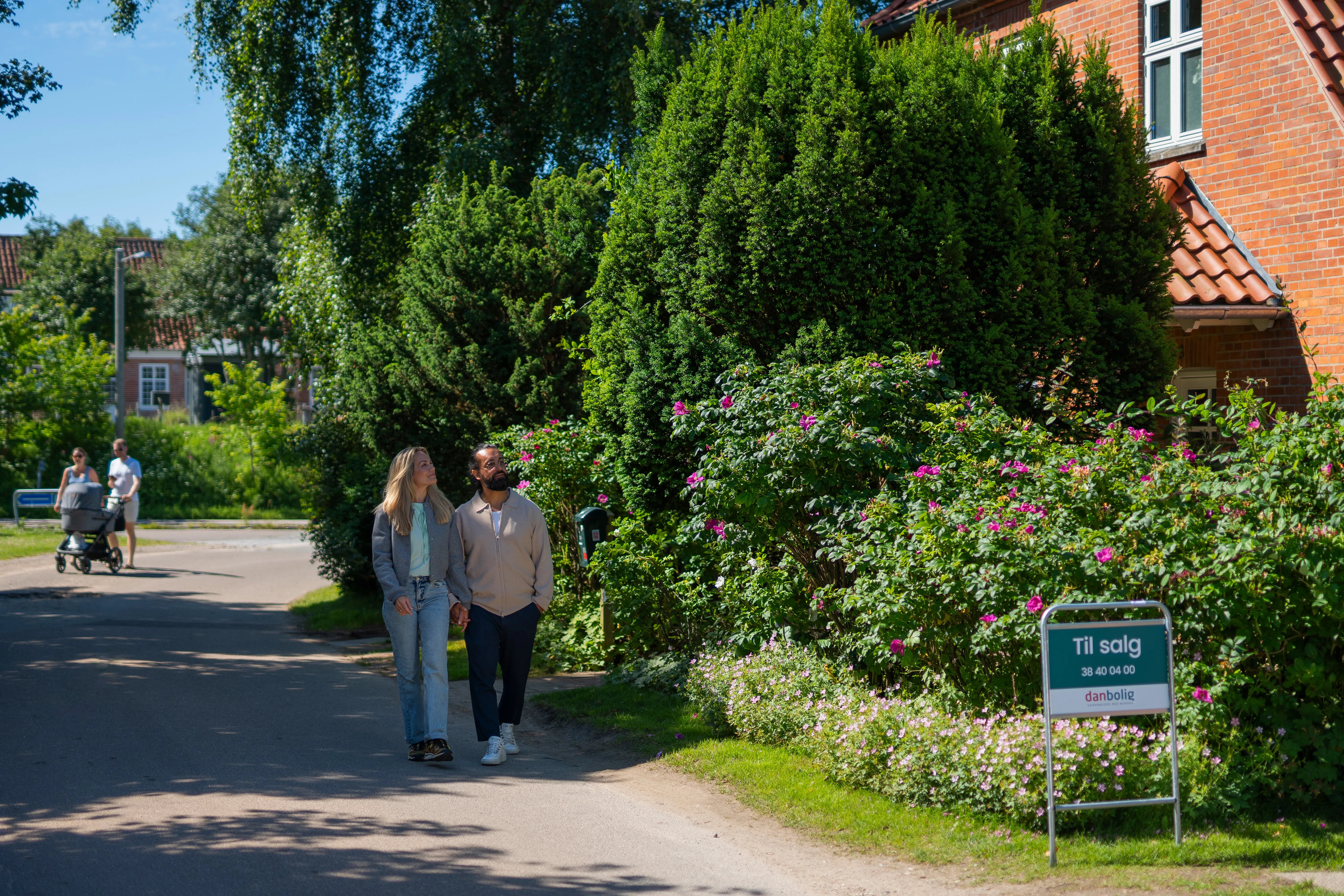 Par går hånd i hånd på villavej og kigger på et hus til salg