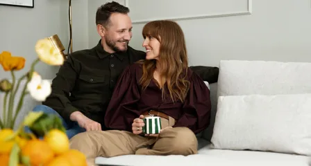 To personer sidder i en hvid sofa og smiler til hinanden