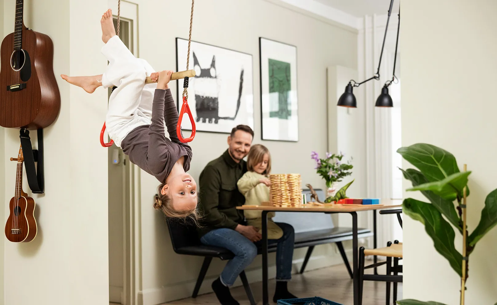 Barn svinger i trapez i d&#xF8;rkarmen, mens far kigger p&#xE5; i baggrunden