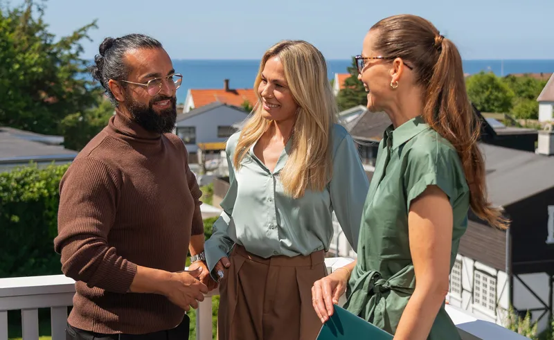 Par står med ejendomsmægler på terrasse på potentiel bolig