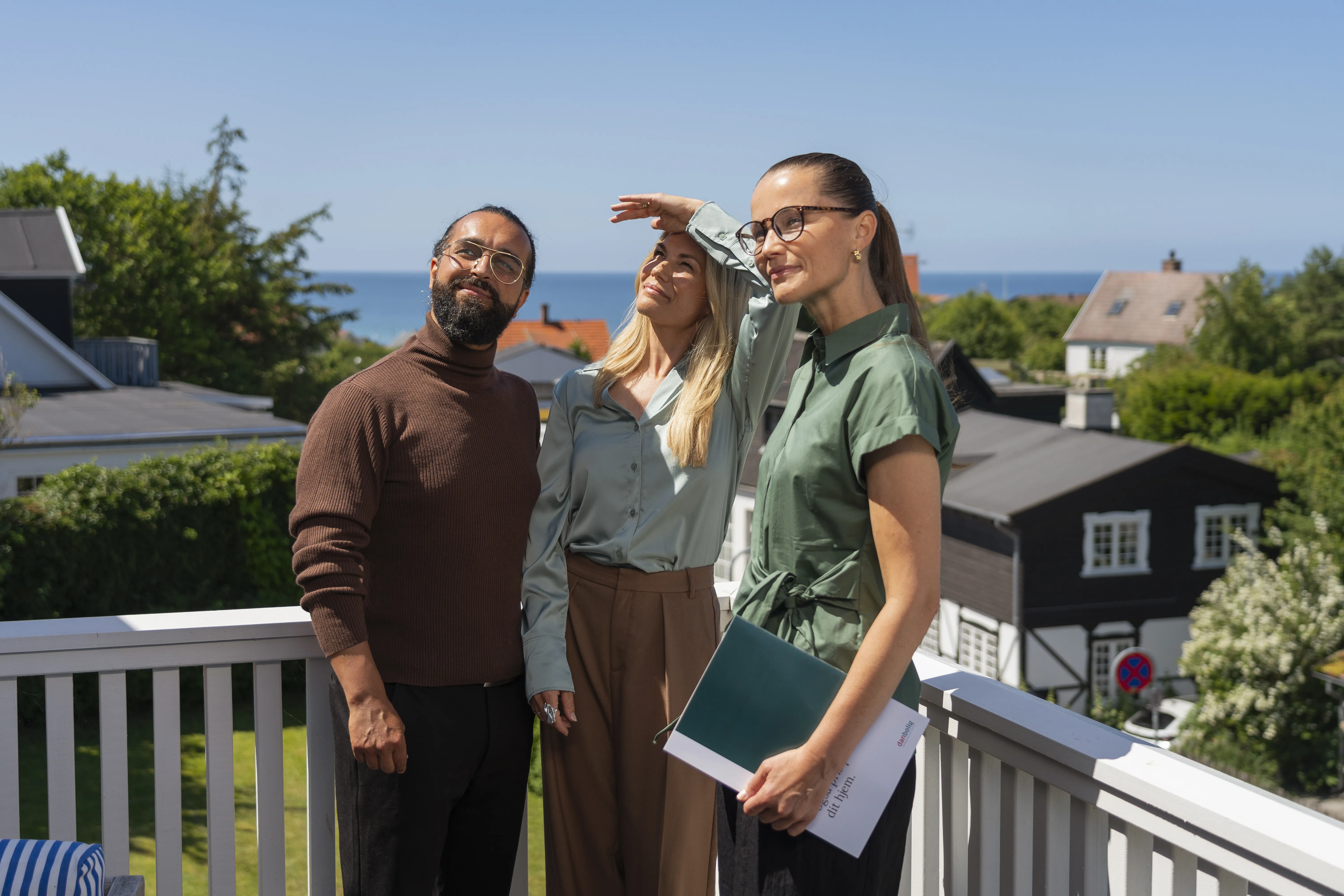 Par står med ejendomsmægler på terrasse og kigger op på villa