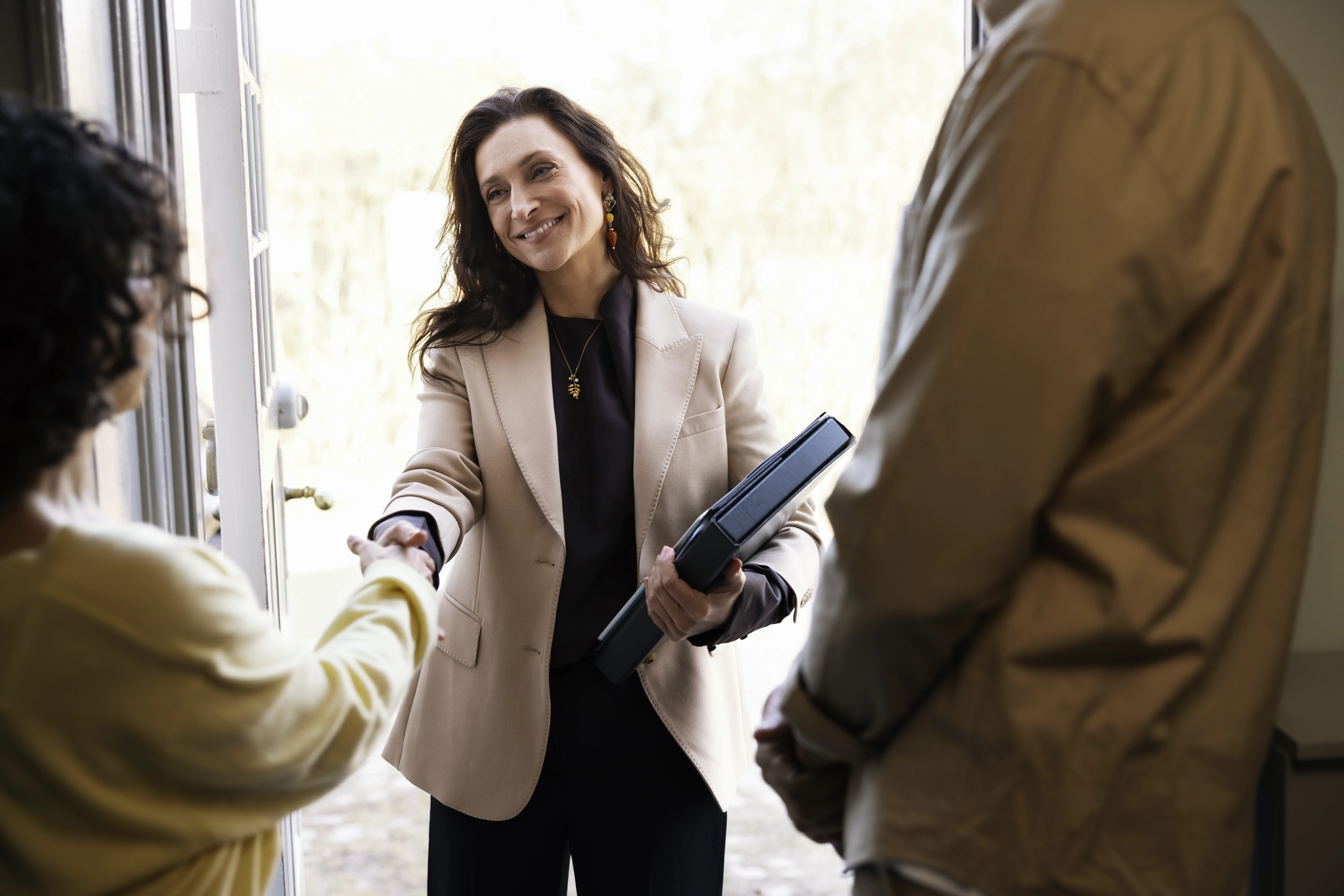 Ejendomsmægler giver håndtryk i døråbningen til boligejere