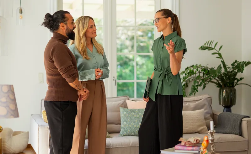 Ejendomsmægler fremviser stue på villa til potentielle boligkøbere