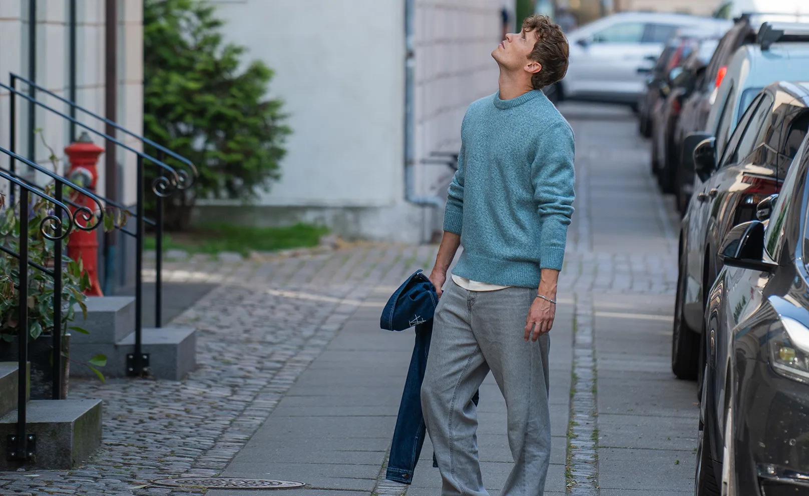 Ung mand står på gaden og kigger op på lejlighedsbyggeri